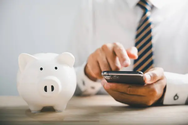 Saving money in piggybank. Mobile banking and budgeting concept with smartphone. Growing fund on white desk. Financial support banner. white background. Financial Money Advice