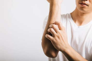 Asian man experiences itchiness on his arm, possibly due to a mosquito bite. Studio shot isolated on white background, depicting discomfort and allergy symptoms like dermatitis and scabies. clipart