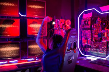 Kazanmak. Oyun kulaklığı takan, video oyunu oynayan genç bir kadın Neon Room 'da heyecanlanıyor, Happy Gamer' ın gençliği online video oyunları oynuyor elini kaldırıp turnuvayı kazanıyor, E-Sport