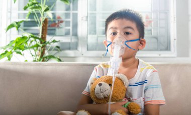 Asian Child using nebulizer mask equipment alone have smoke, Kid boy making makes inhalation nebulizer steam sick cough at home, oxygen spray inhaler therapy, stuffy nose and runny, Health medical