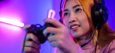 You win. Gamer using joystick controller plays online video game with computer neon lights she winning, woman wear gaming headphones playing live stream esports games console at home celebrating win