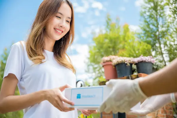 Delivery man give medicine drug store to patient female at front home, healthcare medicine online business, Asian woman sick she receive medication first aid pharmacy box hospital delivery service
