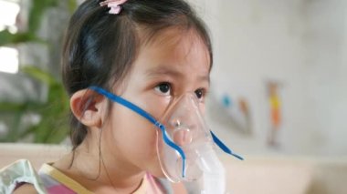 Kid girl making makes inhalation nebulizer steam sick cough at home, Asian Child using nebulizer mask equipment alone have smoke, stuffy nose and runny, oxygen spray inhaler therapy, Health medical