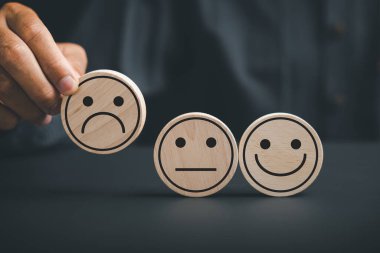 Müşteri memnuniyetsizliği konsepti. Müşteri ahşap çemberde somurtma ikonu tutuyor, tatminsizliği simgeliyor. Mutsuz bir müşteriyi, olumsuz tepkiyi ve hayal kırıklığını ifade etmek..
