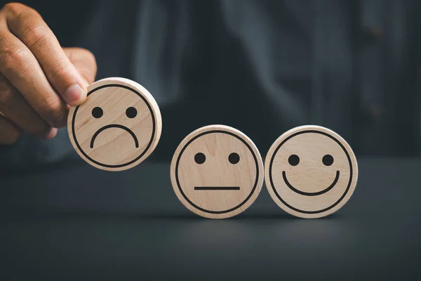 Customer dissatisfaction concept. customer holds frown icon on wooden circle, symbolizing poor satisfaction. Depicting an unhappy customer, negative feedback, and disappointment.