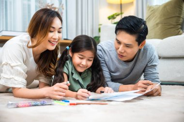 Gülümseyen baba, anne ve kız evdeki kağıt üzerine resim çiziyorlar, Asyalı aile oturma odasında kızıyla birlikte resim yapıyor, mutlu aile aktiviteleri öğreniyor, resim çizmeyi öğreniyor.