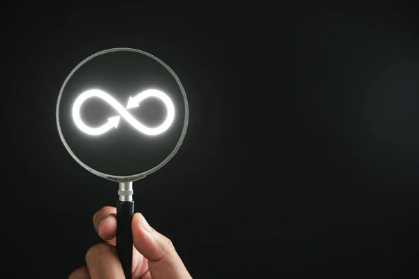Magnifying glass reveals infinity symbol icons, symbolizing future sustainable investment growth. Technology and data concept. the idea of future-focused investment. Technology infinity data