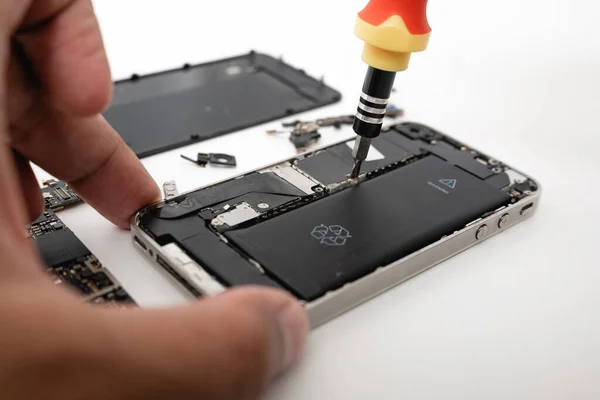 Technician repairing inside the smartphone motherboard with tools for recovery, The man repair by tightening nut from mobile phone with a screwdriver to fix problem