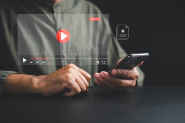 Çevrimiçi medya dünyasını akıllı bir telefonla aç. Genç bir adam film izlemekten zevk alıyor. Dijital eğlencenin kolaylığını ve esnekliğini her yerde keşfedin..