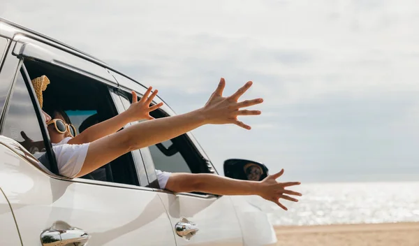 握紧手 快乐的一家人坐在车里挥手旅行 走出车窗去海滩旅行 人们在外面的路上玩得开心 — 图库照片