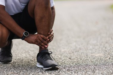Kapatın Asyalı genç spor koşucusu. Siyah adam kol eklemli el takıyor. Ayak bileği burkulduğu için bacak ağrısı çekiyor.