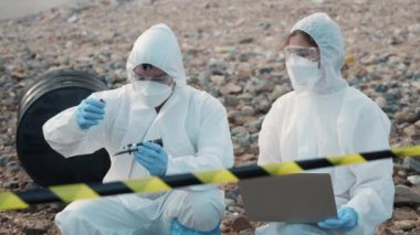 Nehirden suya kadar suyu inceleyen ekolojist biyolog koruyucu giysi giyiyor ve endüstriden pH ölçer için atık su örneği topluyor, sorun ortamı