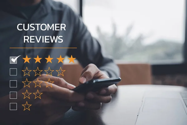 Digital technology is changing business operations. A mans hand using a laptop and smartphone with a 5-star rating icon for customer service satisfaction and online survey