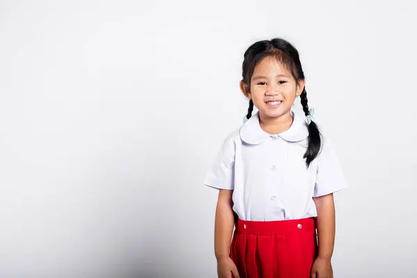 亚洲可爱的蹒跚学步的孩子喜形于色 穿着学生制服红色的裙子站在工作室里 孤零零地望着白色的背景 描绘着年幼的孩子们上幼儿园 快乐的孩子回到学校 — 图库照片
