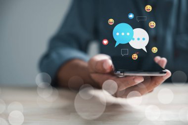 Dahili ofis bağlantıları olan adam akıllı telefondan sohbet ediyor, canlı sohbet ve sosyal ağ kavramlarını tartışıyor. Modern iletişimi gösteren sohbet kutusu simgeleri ortaya çıkıyor. Sosyal medya pazarlama teknolojisi