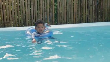 Yüzme havuzunda oynayan mutlu çocuk, şişme yüzükte kıvırcık saçlı mutlu çocuk havuzda eğleniyor ve yaz tatillerinde, tatillerde ve tatillerde sağlıklı açık hava aktivitelerinde tatilde.
