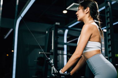 Spor salonunda ağırlık çeken, bisepslerini çalıştıran ve kas gücünü arttıran formda bir Asyalı kadın. Fitness Merkezi Sağlık Çalışmaları Konsepti