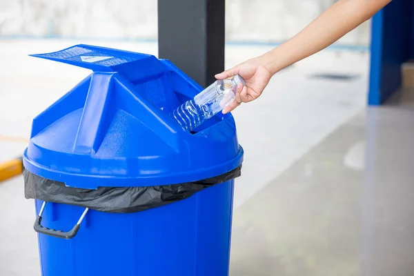Close up female throwing empty bottle to trash, woman hand throwing empty plastic water bottle into blue recycling bin, Recycle rubbish, separate for save the world and environment care