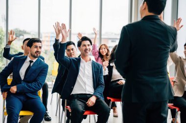 Bir konferans sırasında genç bir adam, aktif katılım işbirliği ve tartışmalara katılımı vurgulayan sorular sormak için elini kaldırır..