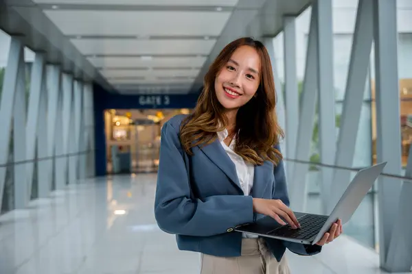 Portrait of young professional woman working remotely with laptop and cellphone in airport, enjoying the convenience of modern technology