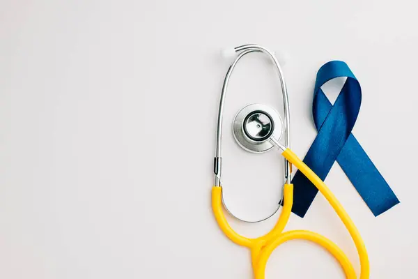 In support of mens health awareness campaigns in November and September, this image features a stethoscope and an awareness blue ribbon. Regular check-ups and care are fundamental.
