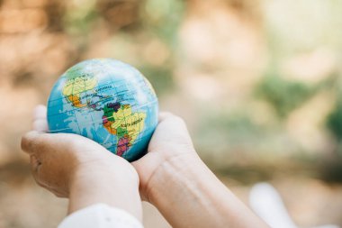 Dünya Gününü Yeşil Enerji, ESG ve Sürdürülebilir Kaynaklar konseptiyle kutlayın. Sorumluluk ve çevre bakımını belirtmek için elinizde yeşil bir yaprak ve küreyi tutun..