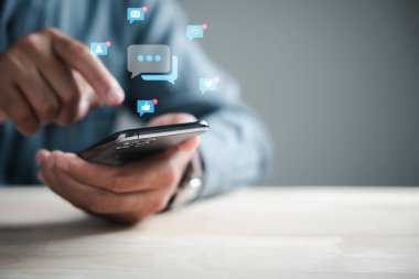Merkez ofisin kurucusu akıllı telefonu devreye sokuyor, canlı sohbet ve sosyal ağ kavramları için daktilo yazıyor. Sohbet kutusu simgeleri, dijital iletişimi ve sosyal medya pazarlamasını sembolize ederek ortaya çıkar.