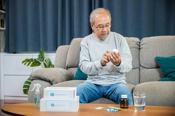Asian worried senior man with medicine pills he read on see how to take pills before taking, old man buy herbal self cure Rx pill online from pharmacy, home isolation, Medical service concept
