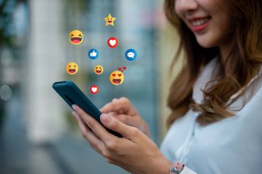 Ara vermenin keyfini çıkarırken akıllı telefonuyla makale okuyan bir kadın. Cihaz dijital bilgi ve eğlenceye erişim sağlıyor ve bu da onu boş zamanlarının önemli bir parçası yapıyor..