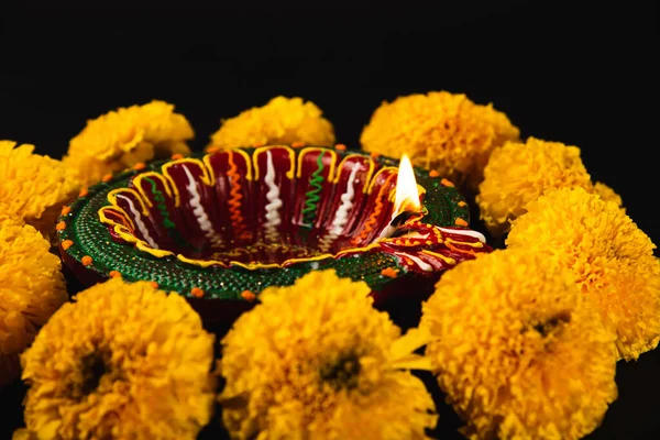 Diwalis charm captured, A radiant Diwali lamp and ornate flower rangoli on a striking black background. Perfect for festive invitations, ceremonies, and celebrations.