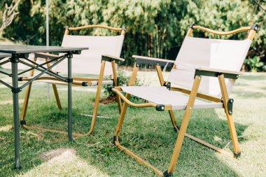 Banliyö avlusunda piknik ve rahatlama için masa ve sandalyeler de dahil olmak üzere çadır barınağı ve kamp malzemeleriyle yaz kampı sahnesi. Çadırın tasarımı gölge ve rahatlık için mükemmeldir..