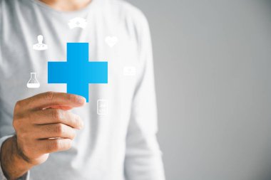Tecrit edilmiş bir erkek elinde artı bir simge, pozitifleri, faydaları, kişisel gelişimi, sağlık sigortasını ve büyümeyi temsil ediyor. Sağlık ve teknolojide yenilik tasvir ediyor.