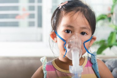 Kid girl making makes inhalation nebulizer steam sick cough at home, Asian Child using nebulizer mask equipment alone have smoke, stuffy nose and runny, oxygen spray inhaler therapy, Health medical