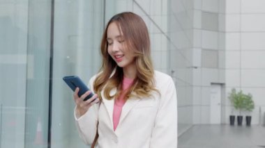 Beyaz tişörtlü genç bir kadın internete bağlanmak ve internette gezinmek için akıllı telefon kullanıyor. Modern dijital cihaz günlük rutininin önemli bir parçası..