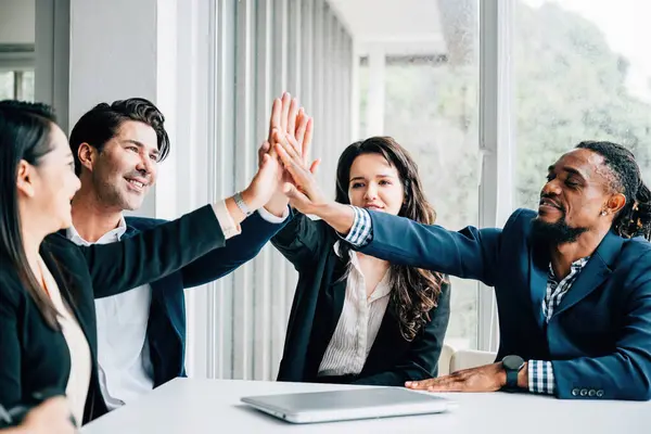 The office atmosphere is charged with positivity as a diverse group of colleagues engages in high-fives during a productive meeting, showcasing their dedication to teamwork and shared success.