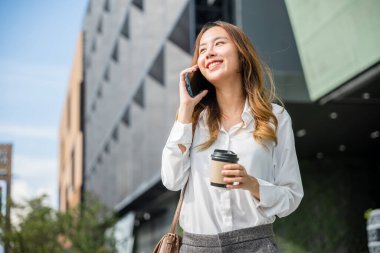 Güzel bir kadın sokakta yürüyor ve ofisin yakınındaki cep telefonundan arıyor. Elinde kahve fincanı taşırken çantasından müşteriye kadar iş kadını portresi yapıyor.