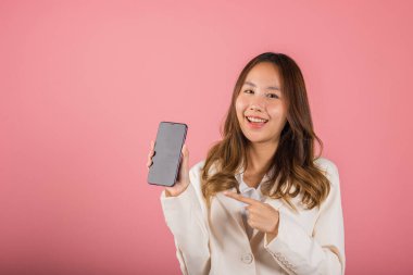 Asyalı mutlu, güzel bir kadının portresi ekrandaki akıllı telefonu işaret ederek online alışveriş uygulamasını işaret ediyor. Kameraya bakıyor.