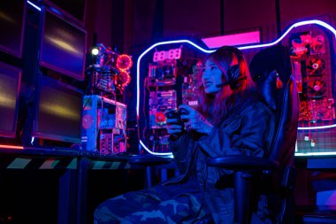 Sanal turnuva için joystick kumandası kullanan oyuncu, bilgisayar neon ışıkları ile çevrimiçi video oyunu oynuyor, kadın canlı akım esport oyunları konsolu oyun odası oyunu oynayan kulaklık takıyor