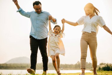 Mutlu bir aile, güneşli bir bahar gününde güzel bir parkta yürüyüşe çıkar, dışarıda olmanın ve sezonun tadını çıkarmanın neşesini ve birlikteliğini hisseder.