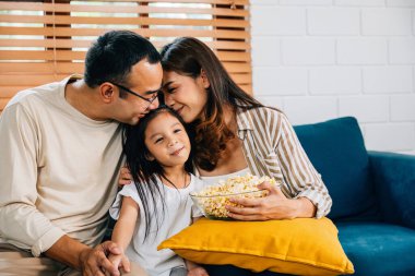 Aile saadeti, kanepede televizyon seyredip patlamış mısır yerken yakalanır. Baba, anne, kız ve kardeş kahkahaları paylaşıyor. Mutluluğu, birlikteliği ve rahatlığı simgeliyor..