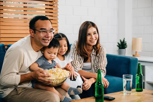 In their cozy living room, a joyful family and their daughter bond over a football match on TV. Their cheers, laughter, and togetherness reflect the joy of winning and celebrating a triumph.