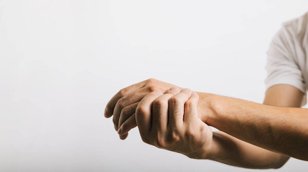 A mans sad portrait, his wrist in pain, possibly due to carpal tunnel syndrome. Studio shot isolated on white background, focusing on health care and the medical concept.
