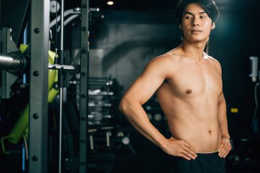 Formda ve formda bir adam, spor salonunda duruyor, koçu ve antrenörüyle birlikte çalışıyor, sağlıklı bir yaşam tarzını benimsiyor. Kopyalama alanı ile sağlıklı fitness