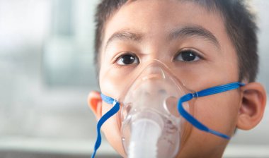 Asian Child using nebulizer mask equipment alone have smoke, Kid boy making makes inhalation nebulizer steam sick cough at home, oxygen spray inhaler therapy, stuffy nose and runny, Health medical