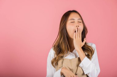 Tulum giymiş güzel bir Asyalı kadın portresi yorgun ve uykulu esneyen ağzı açık, stüdyo resmi pembe arka planda izole edilmiş çekici kadın uykusuzluğu sıkıcı.