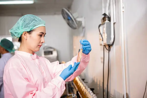 在果汁饮料工厂 女食品工程师使用试管对瓶装产品中的罗勒或奇亚种子进行食品质量和安全测试 强调实验室控制方面的专门知识 — 图库照片