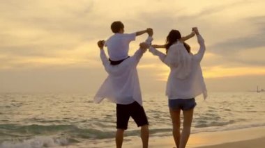 Mutlu aile günleri. Ebeveynler gün batımında çocukları kumsalda omuzlarında taşırlar, baba, anne ve çocuklar yaz tatilinde dışarıda birlikte oynarlar, aile yaz tatilinde seyahat ederler.
