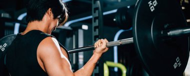 Spor salonunda halteri tutan kaslı bir adam, bir spor portresi için etkileyici kaldırma becerilerini ve atletik vücudunu sergiliyor. Güç kaldırma eğitim kavramı