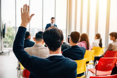 Çeşitli bir gruptaki meraklı şahıs konferans sırasında elini kaldırır. Bu aktif katılımda işbirliği takım çalışması ve tartışmalara katılım sergileniyor.