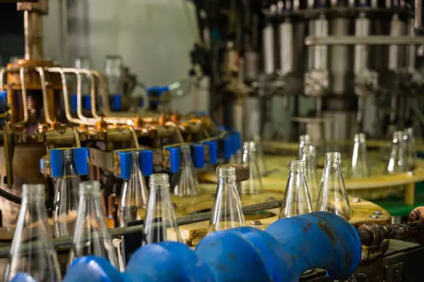 Empty glass bottles on a conveyor showcase the modern distillerys alcoholic beverage manufacturing. Clean automated machinery promises efficient production and bottling.